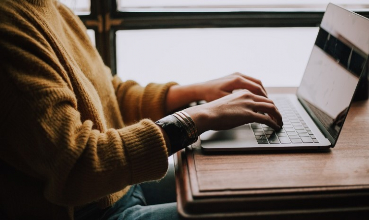 Erfolg als Freiberufler Headerbild: Eine Frau sitzt an ihrem Laptop und schreibt.
