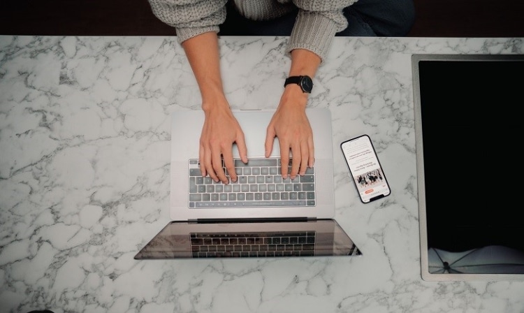 Person arbeitet mit Laptop an Marmor-Schreibtisch