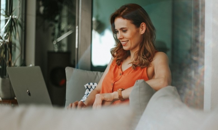 Frau arbeitet mit Laptop auf Couch