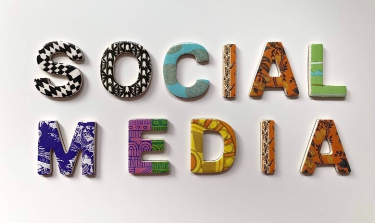 Die Worte Social Media sind auf einem weißen Hintergrund in bunten Holzbuchstaben ausgelegt.